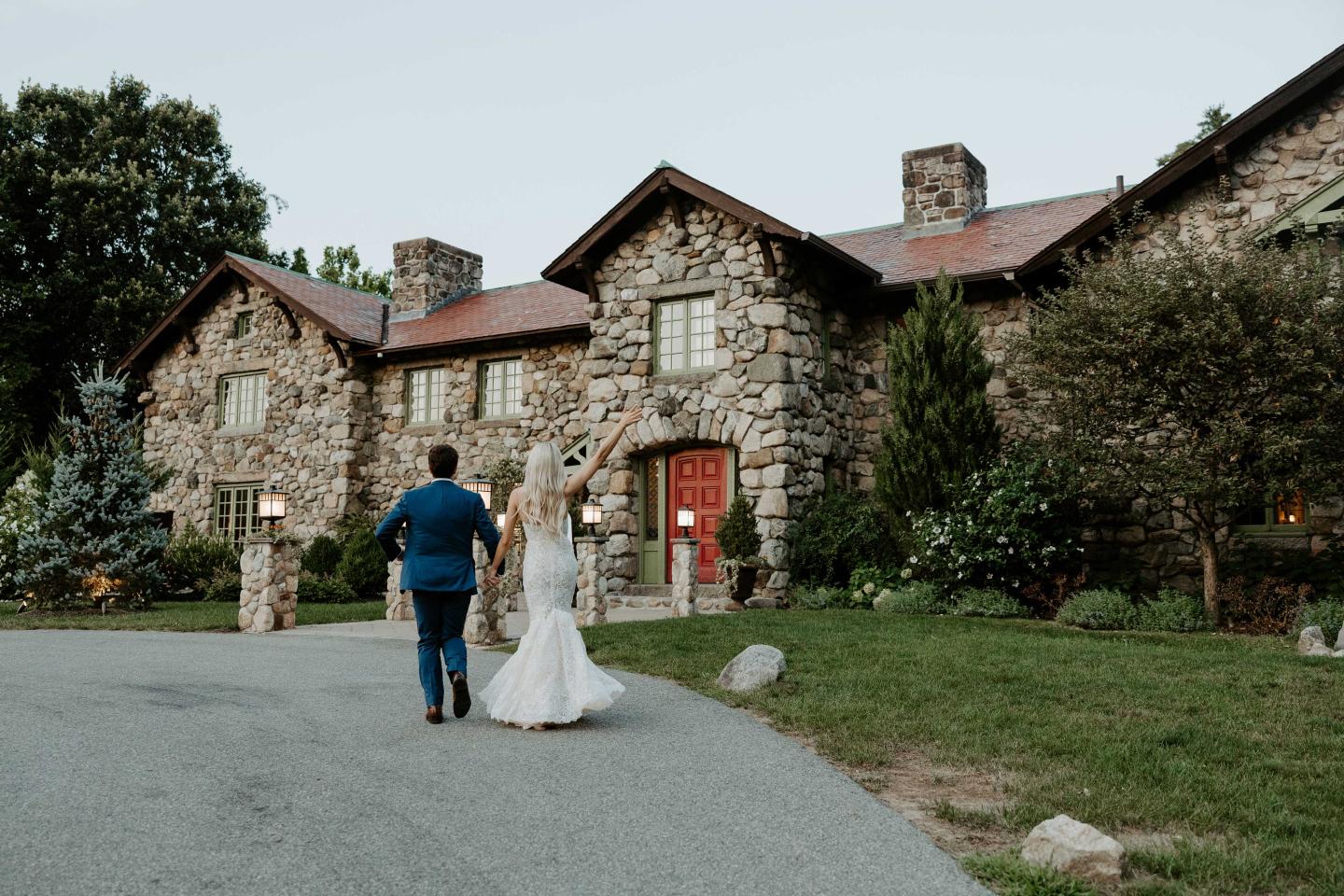 A bride and groom walking towards a mansion