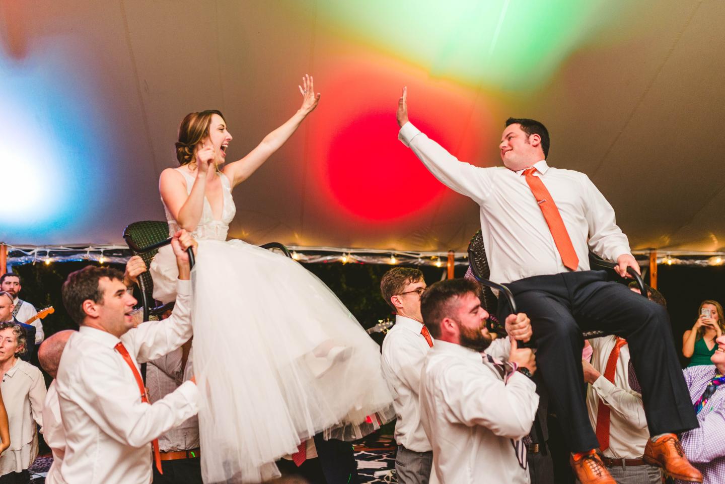 A bride and groom being held up by their guests