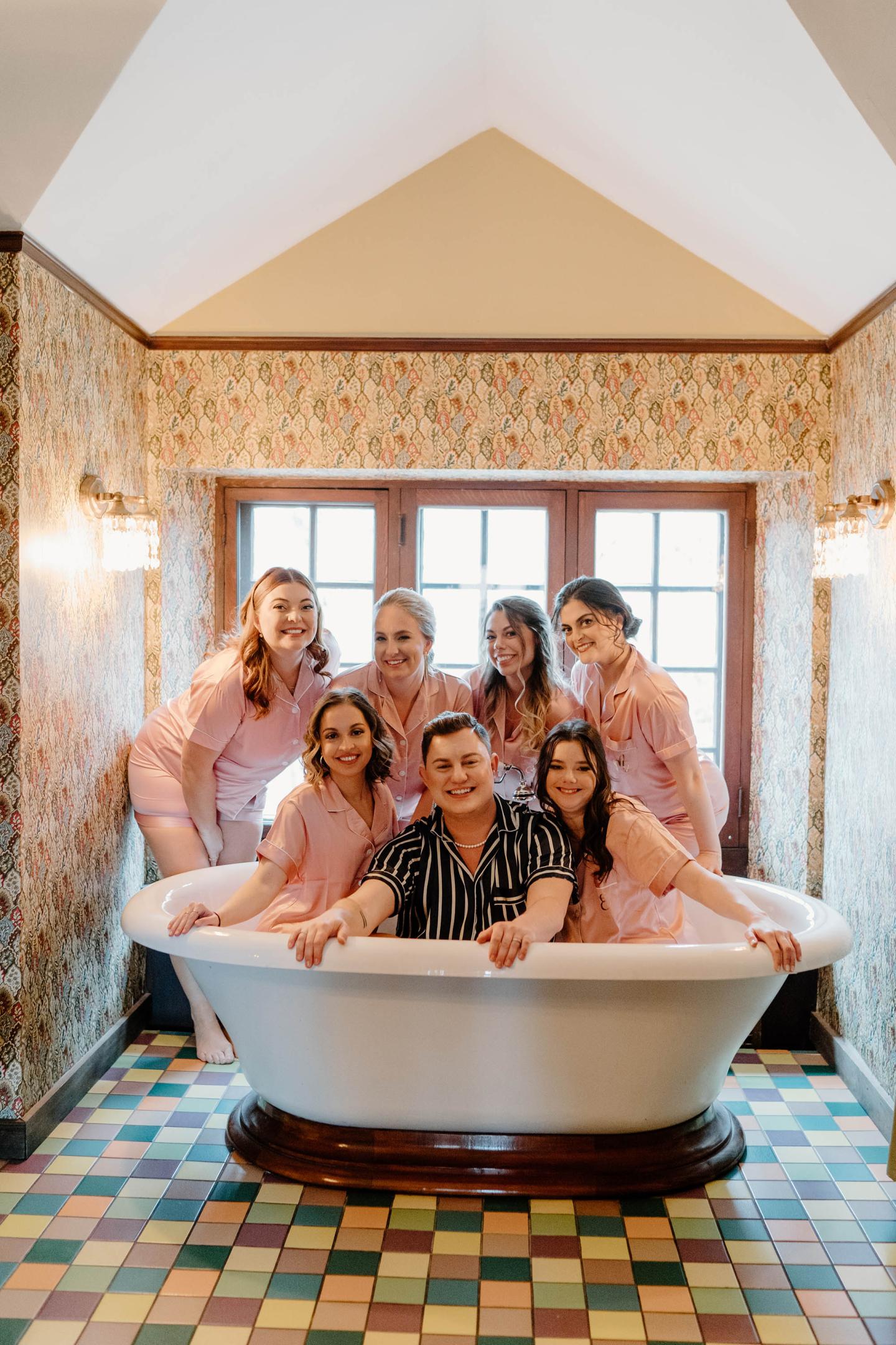 A wedding party posing in a tub