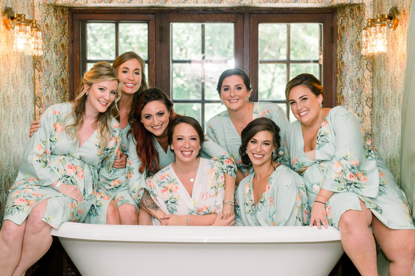 A bride and her bridesmaids posing in a tub