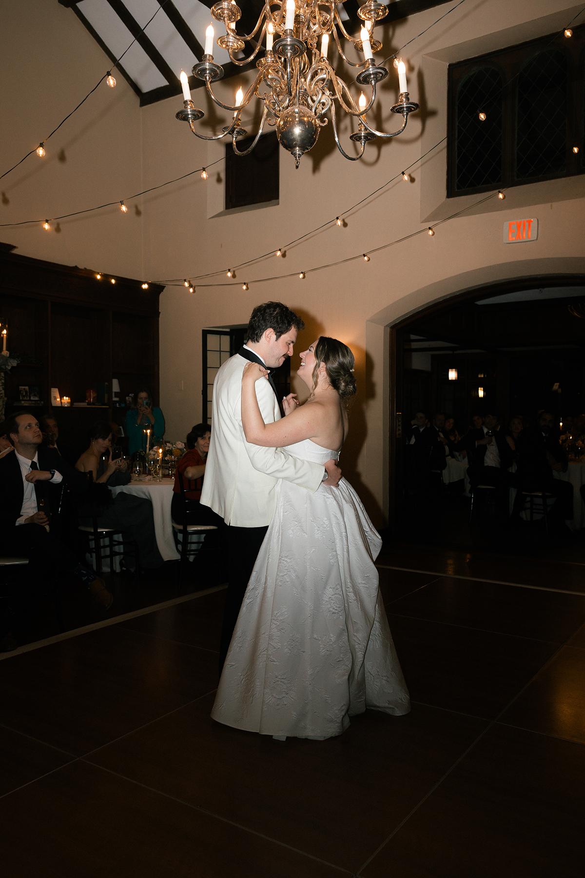 Bride and groom dancing under a chandelier 