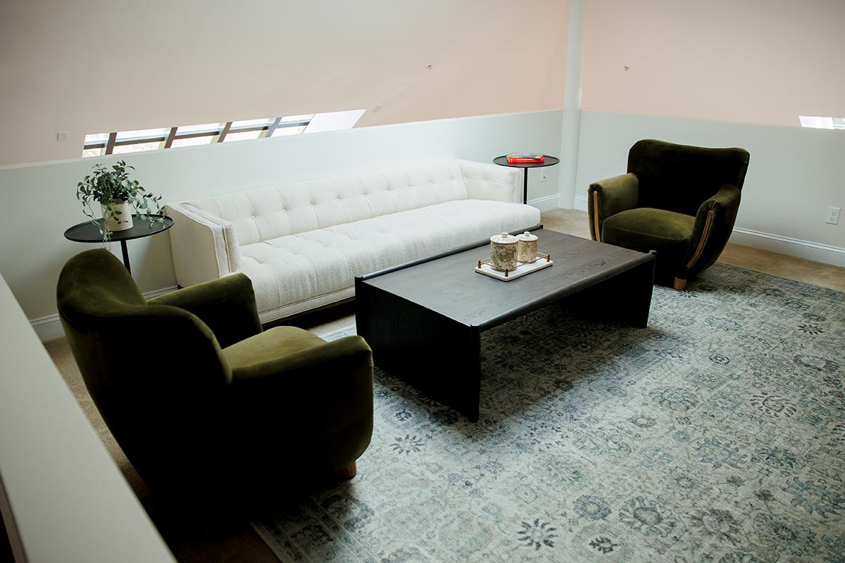 Cozy living room with white sofa, green chairs, and wooden coffee table.