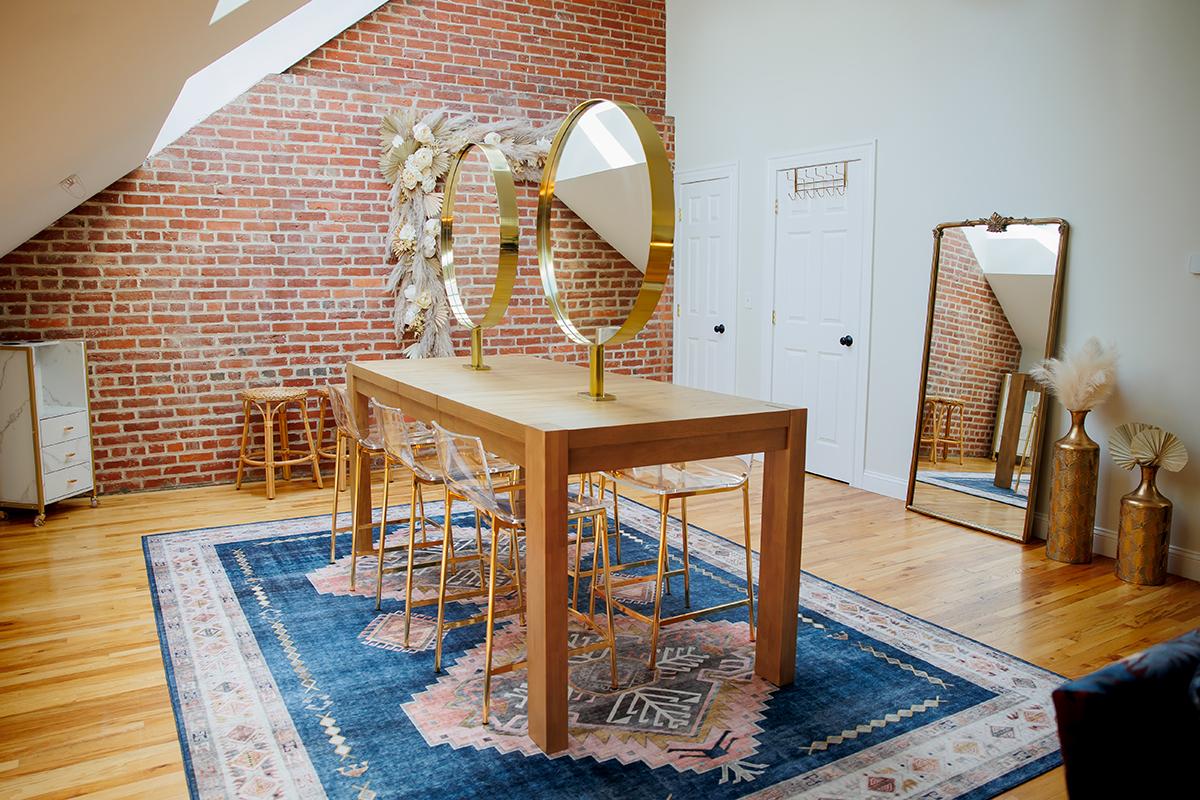 Loft room with a wooden table, round mirrors, and a blue rug.