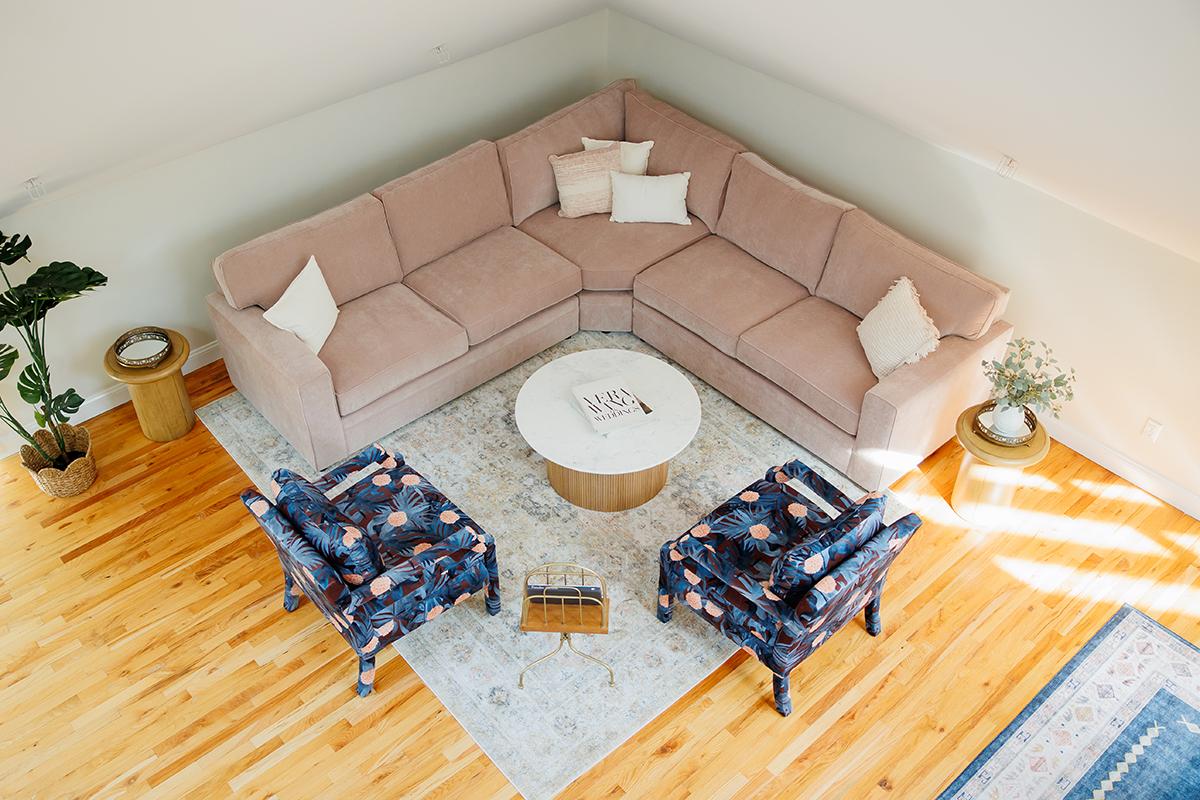 Cozy living room with a pink sectional, two floral chairs, and a round coffee table.