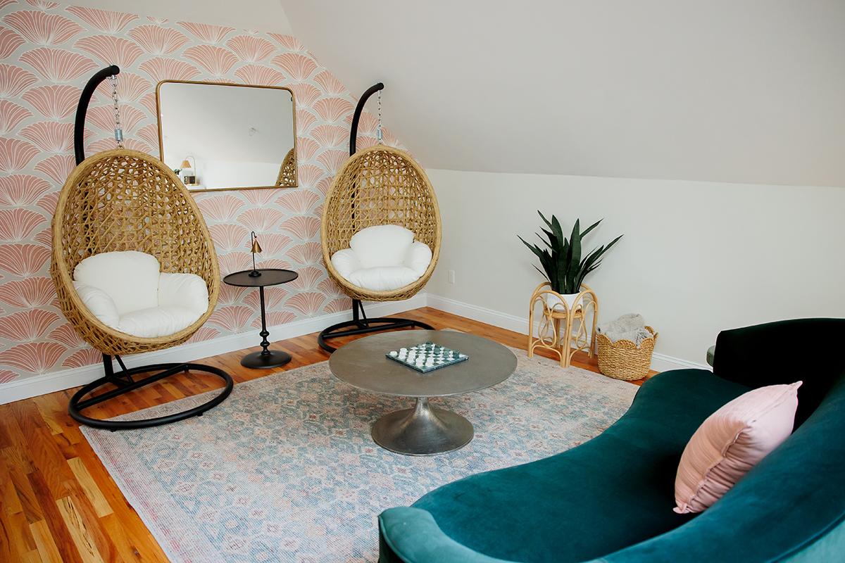 Cozy room with hanging chairs, round table, and green sofa.
