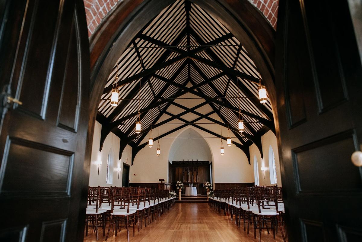 Elegant chapel interior with wooden beams and rows of chairs.