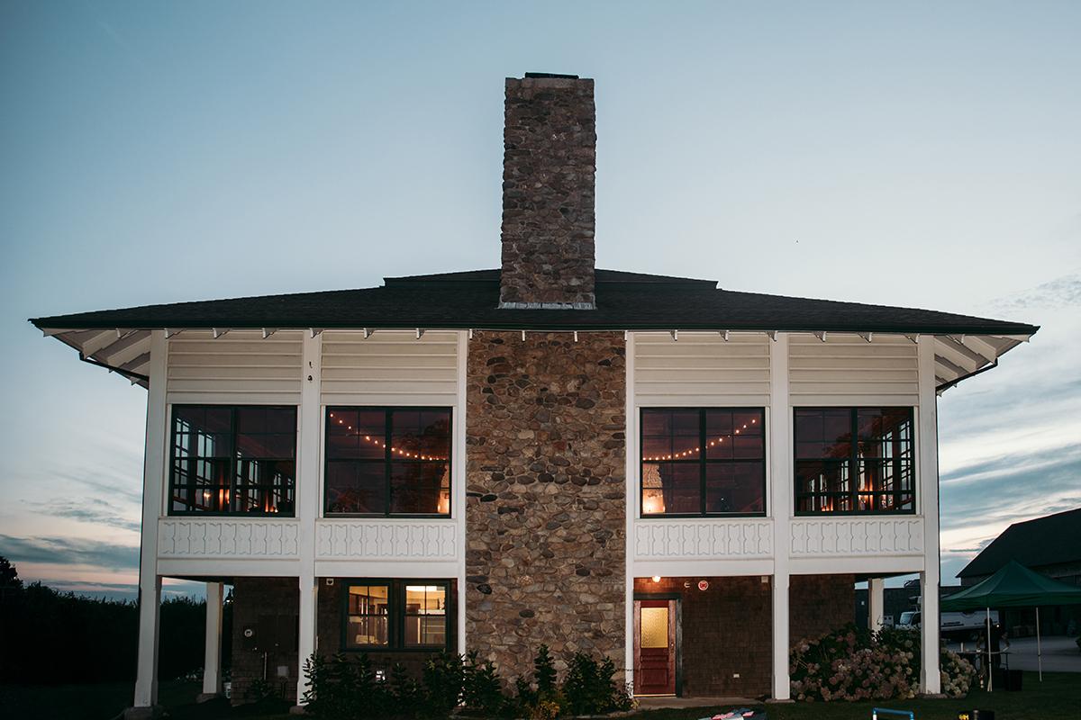 Two-story house with a stone chimney at dusk.
