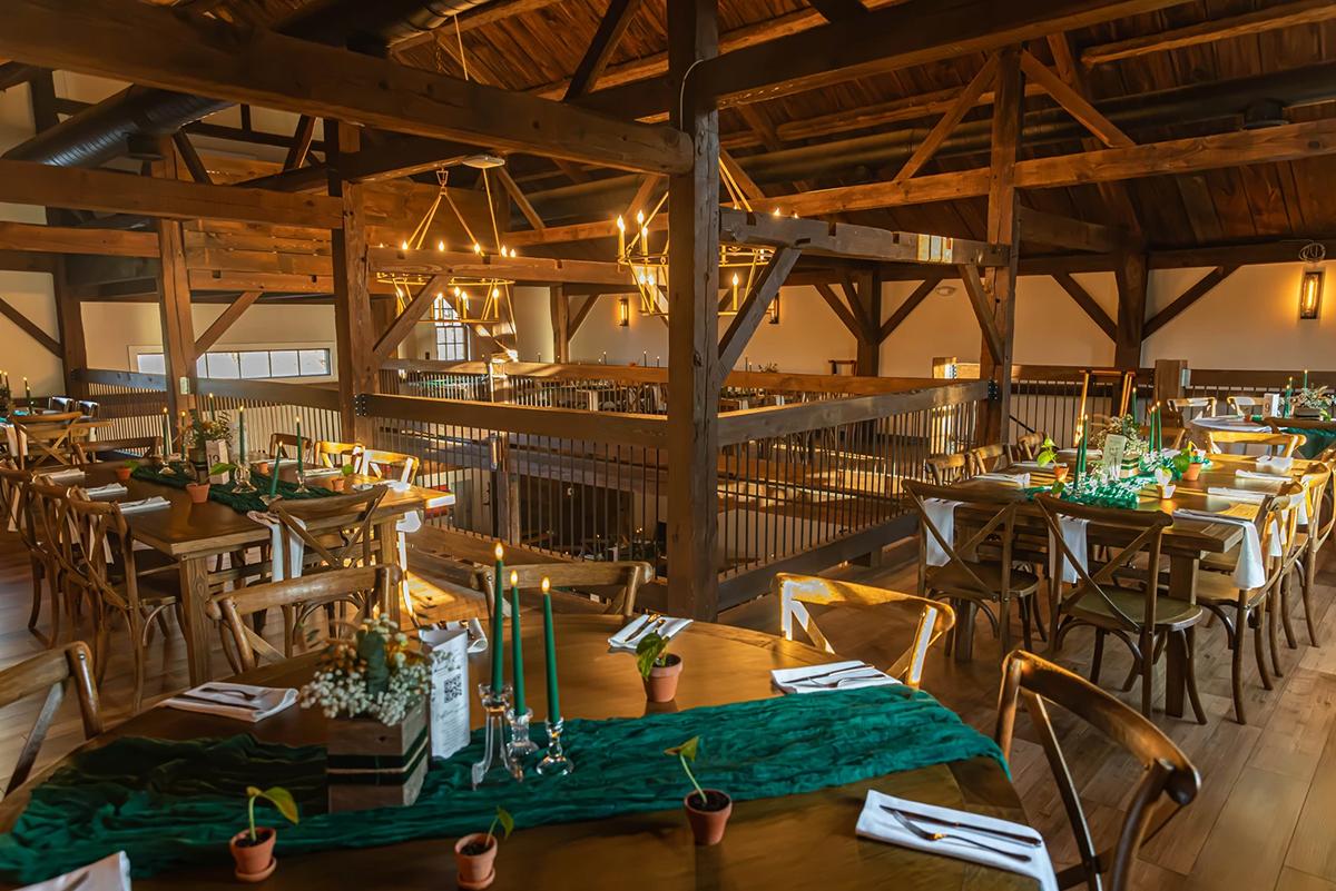 Rustic banquet hall with wooden beams and elegantly set tables.