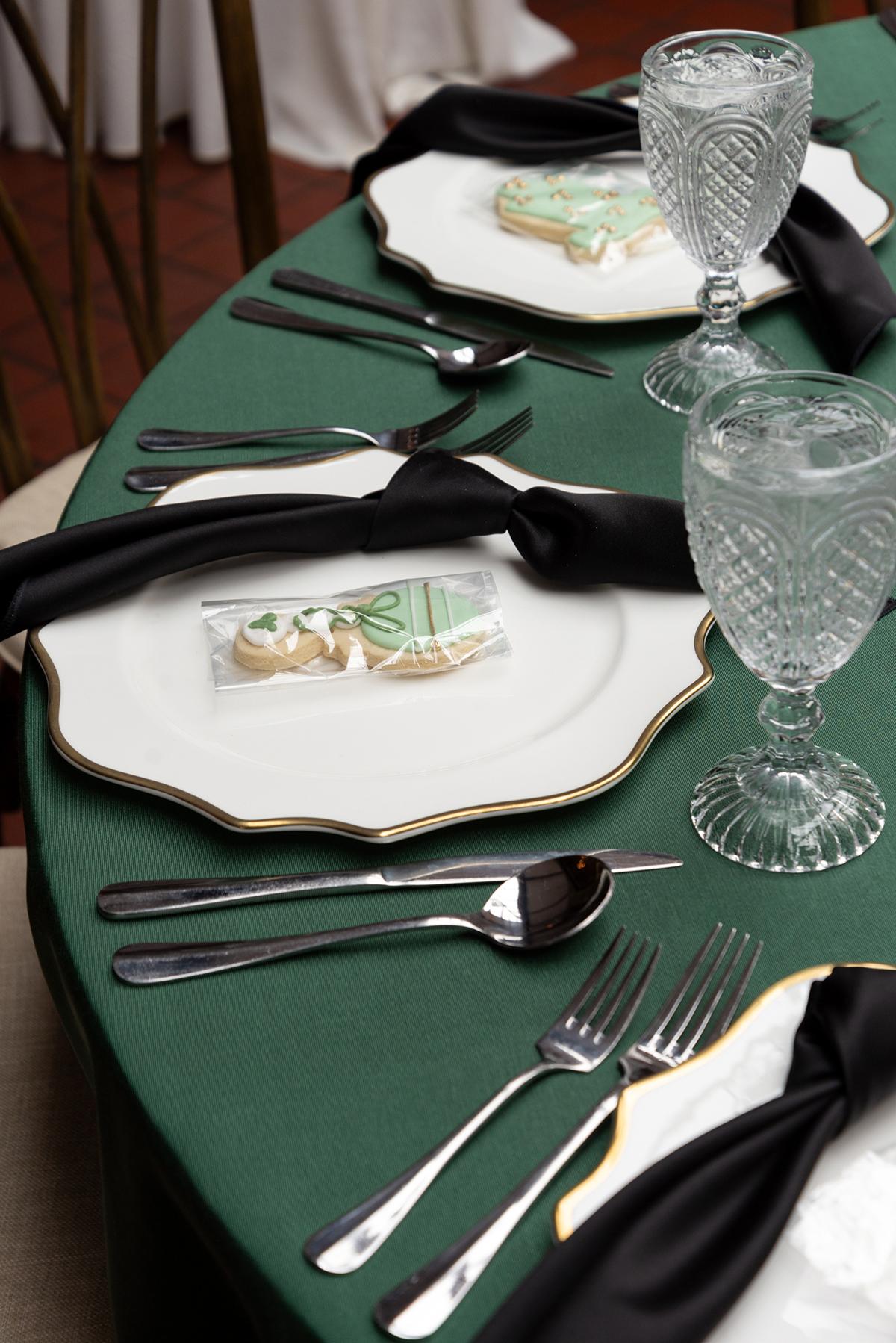 Elegant table setting with green tablecloth, white plates, and crystal glasses.