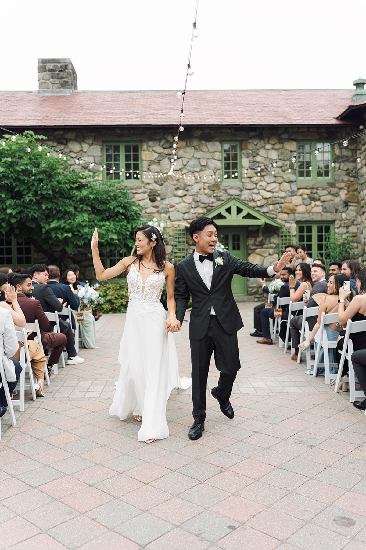 Bride and groom walking down aisle at outdoor wedding ceremony.