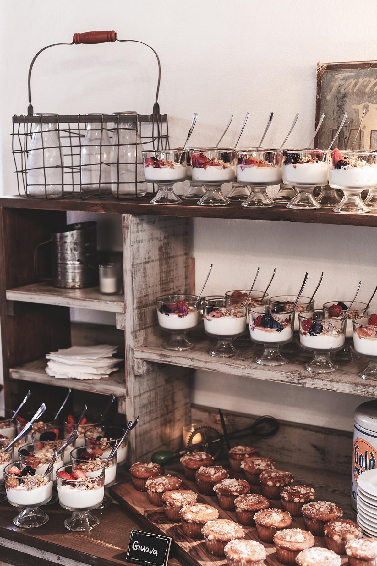 Desserts on shelves, including parfaits and muffins with spoons.