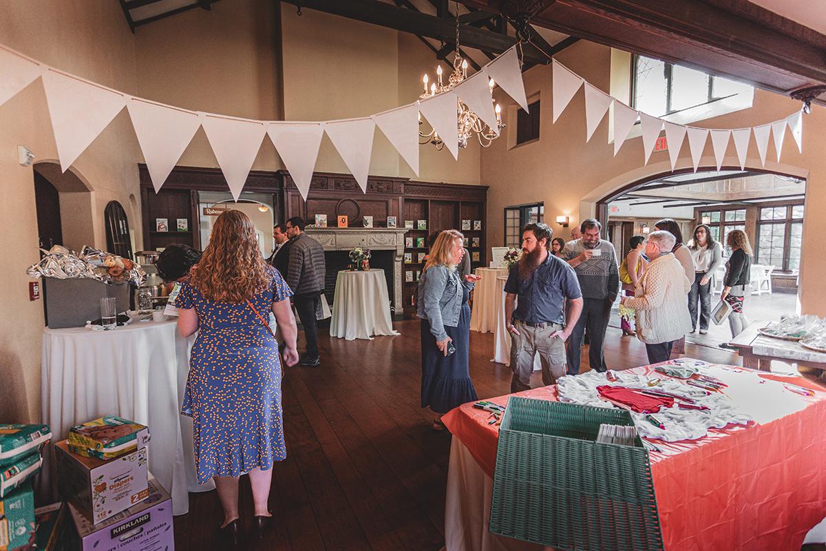Elegant indoor gathering with people socializing, triangular banners, and decorated tables.