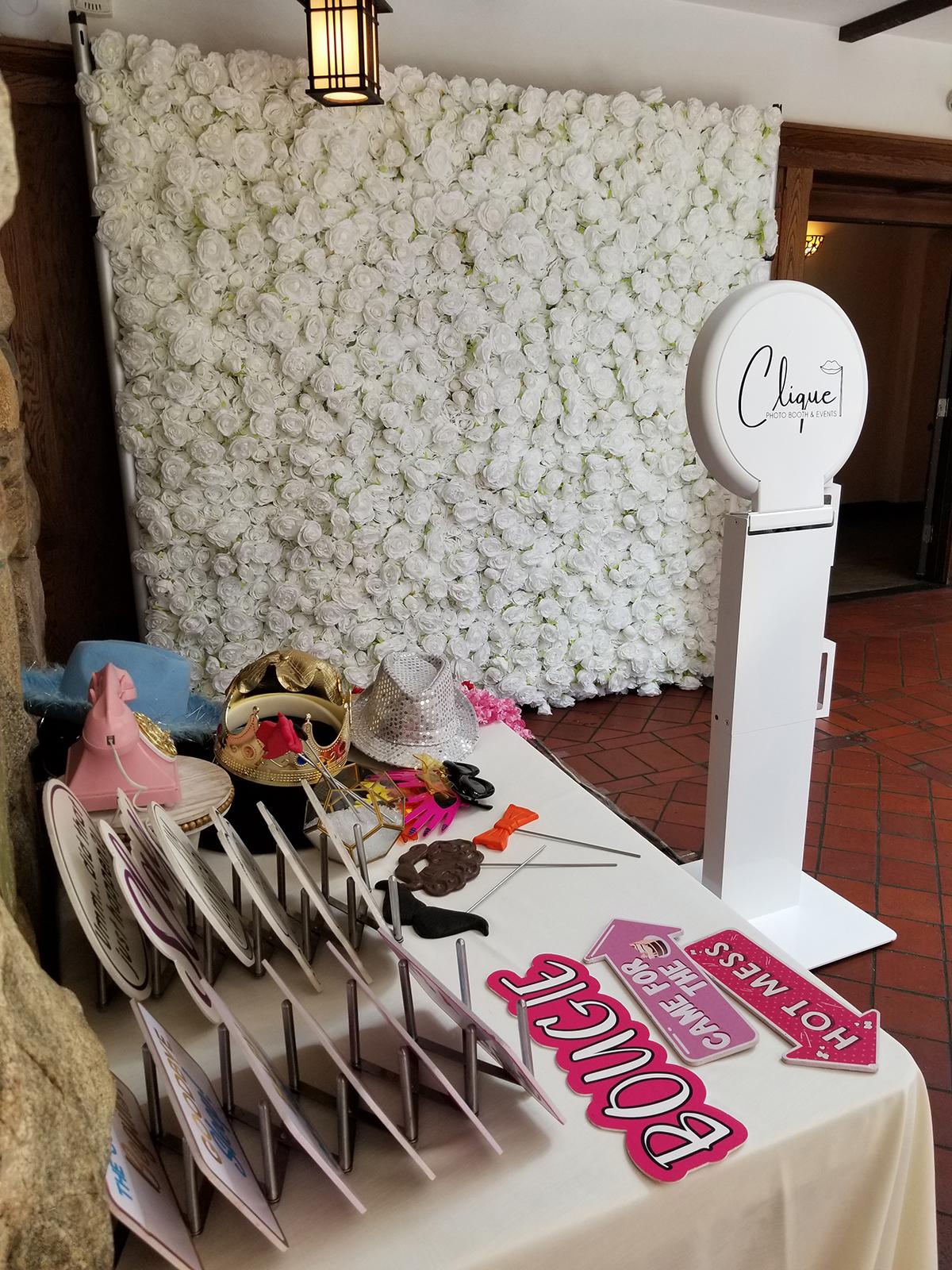 Photo booth setup with white floral backdrop and table of props.