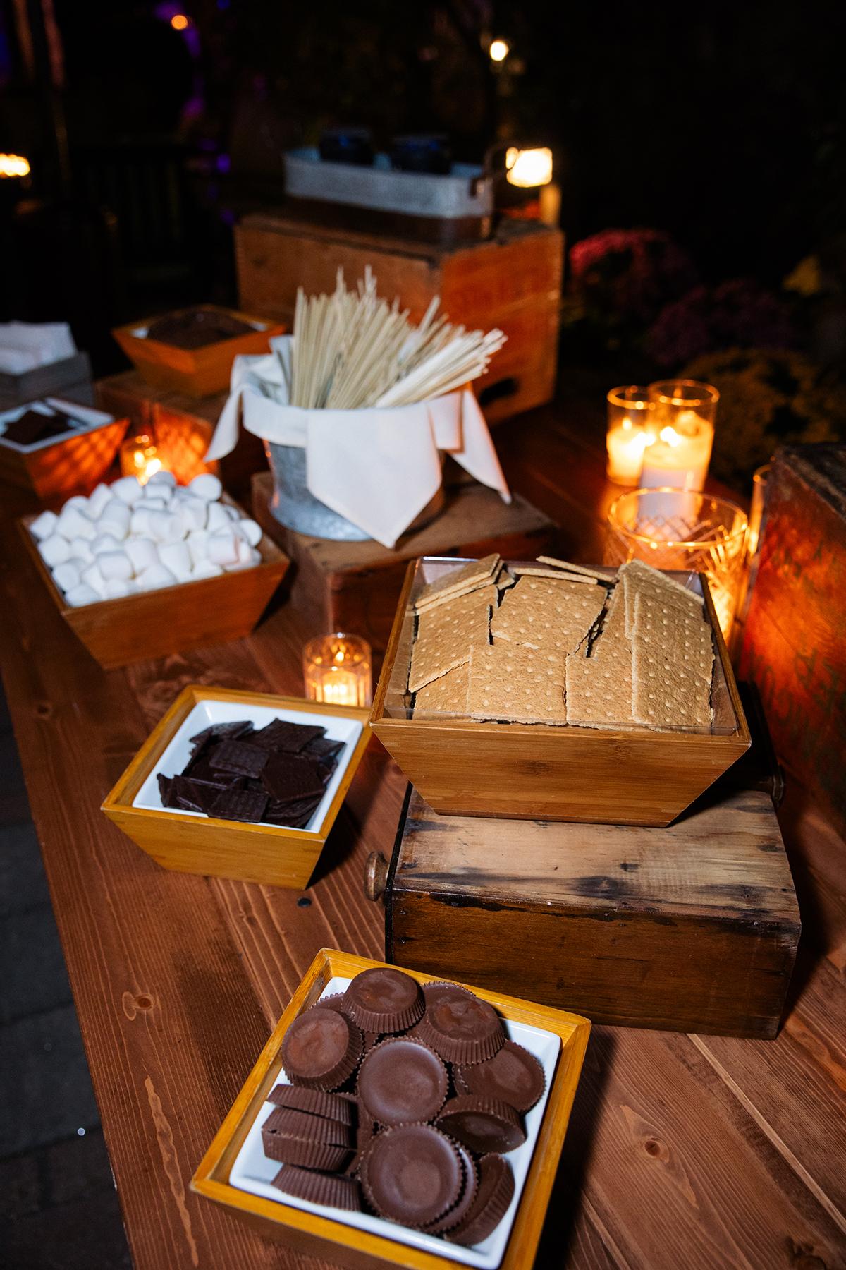 S'mores ingredients on a wooden table with candles.