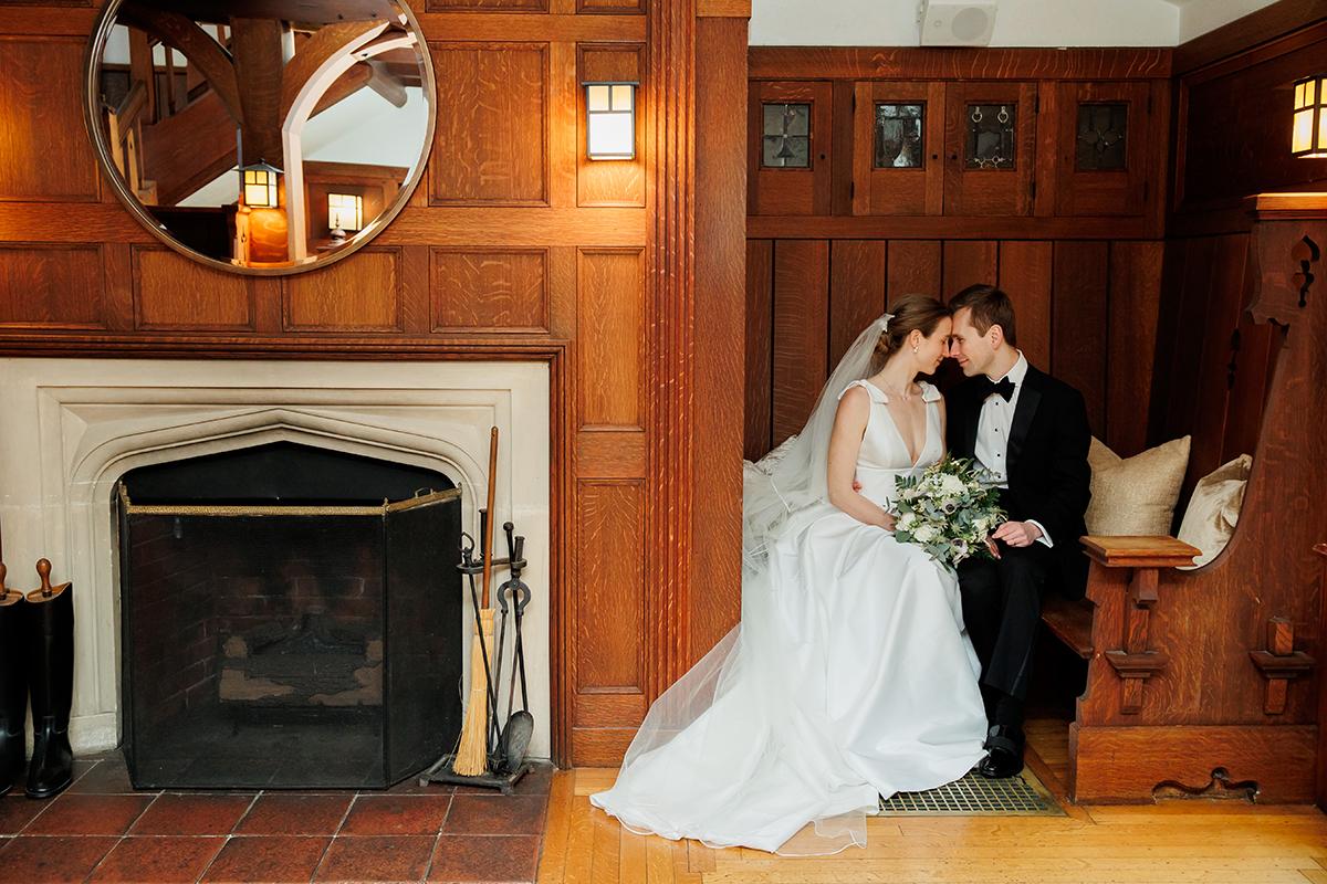 Bride and groom seated in a wooden alcove, sharing a tender moment.