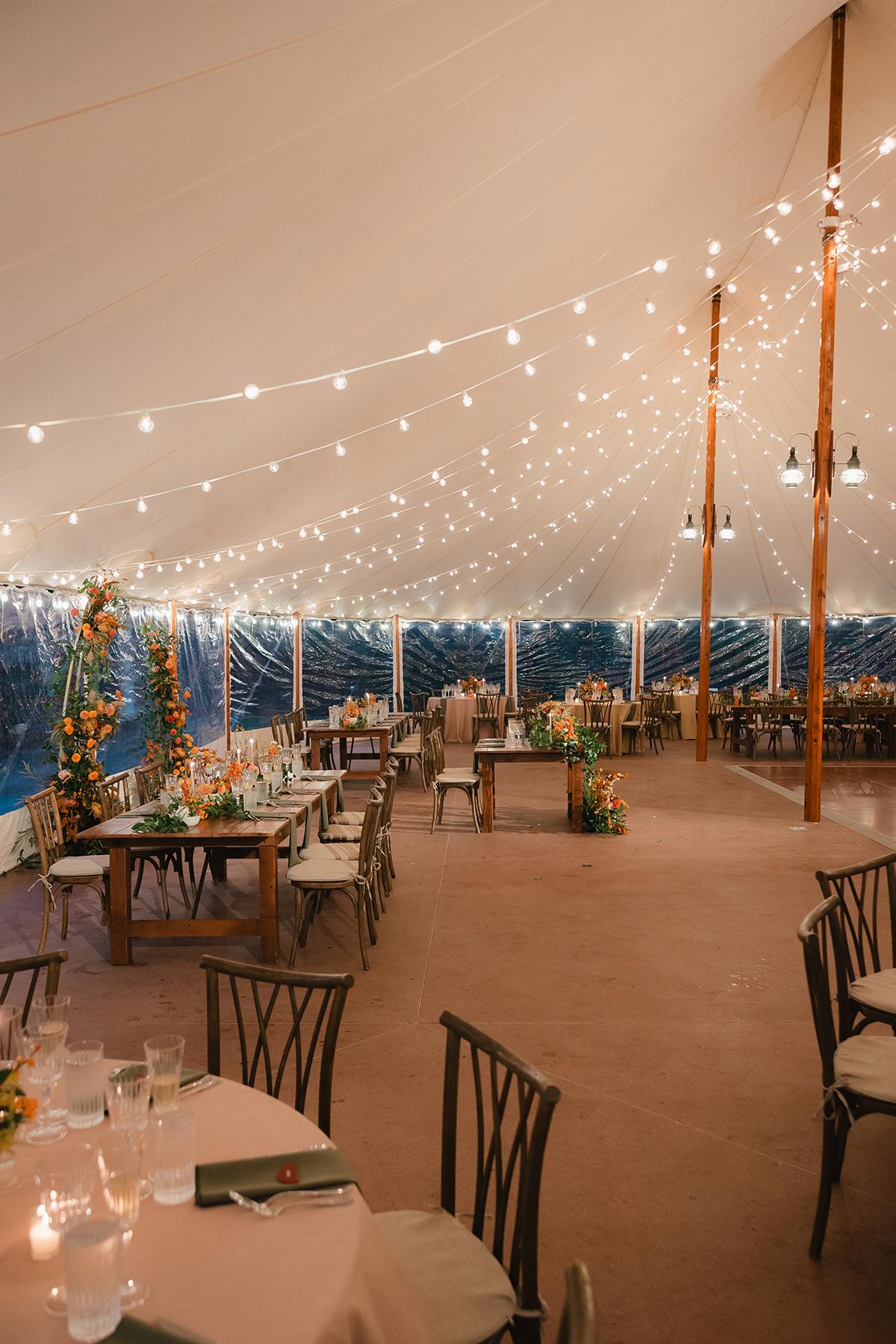 Elegant outdoor tent with string lights and banquet tables.