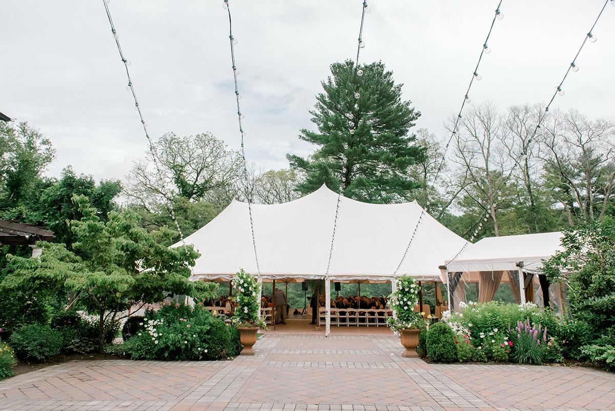 White event tent on a paved area, surrounded by greenery.