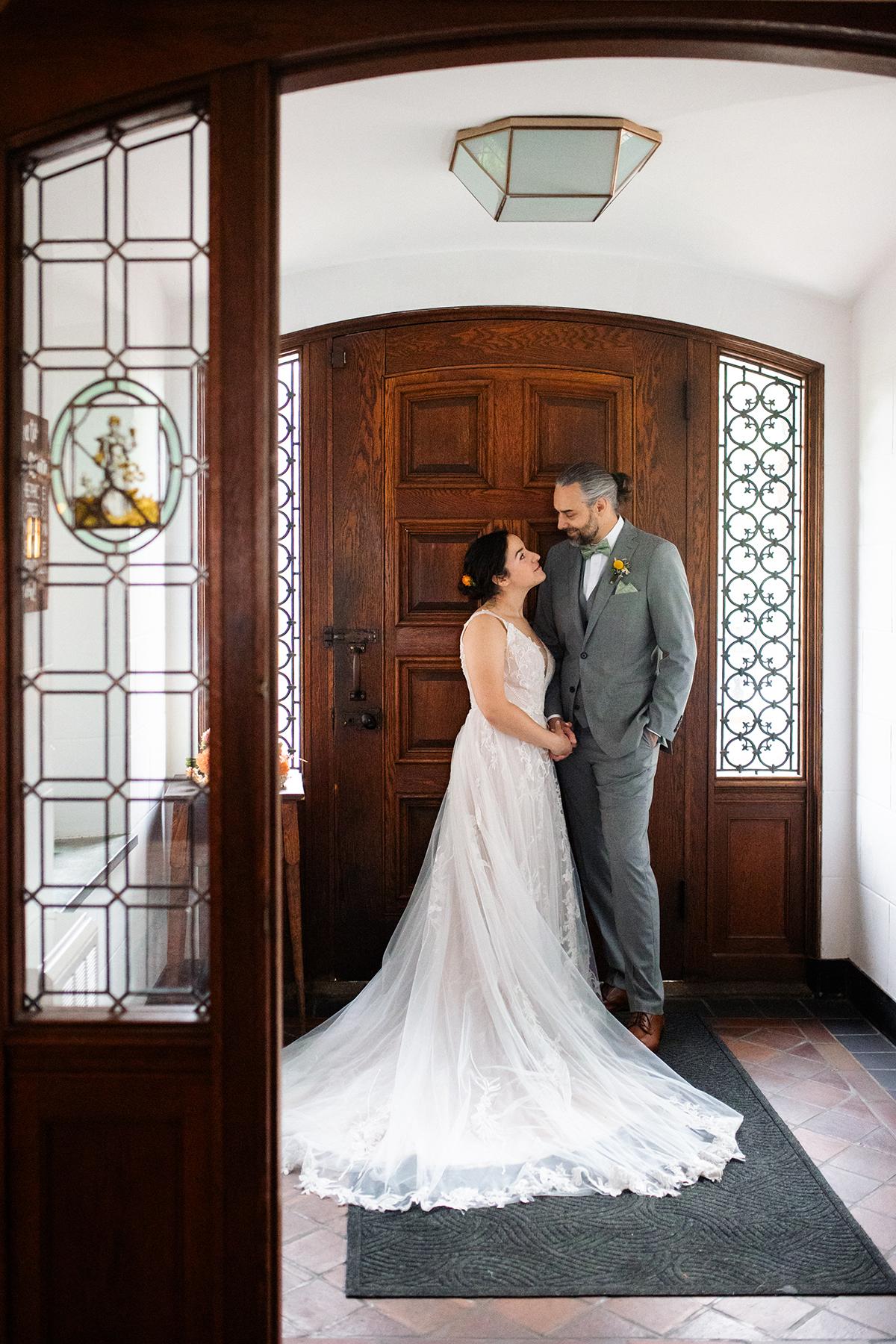 Bride and groom smiling in front of a wooden door.