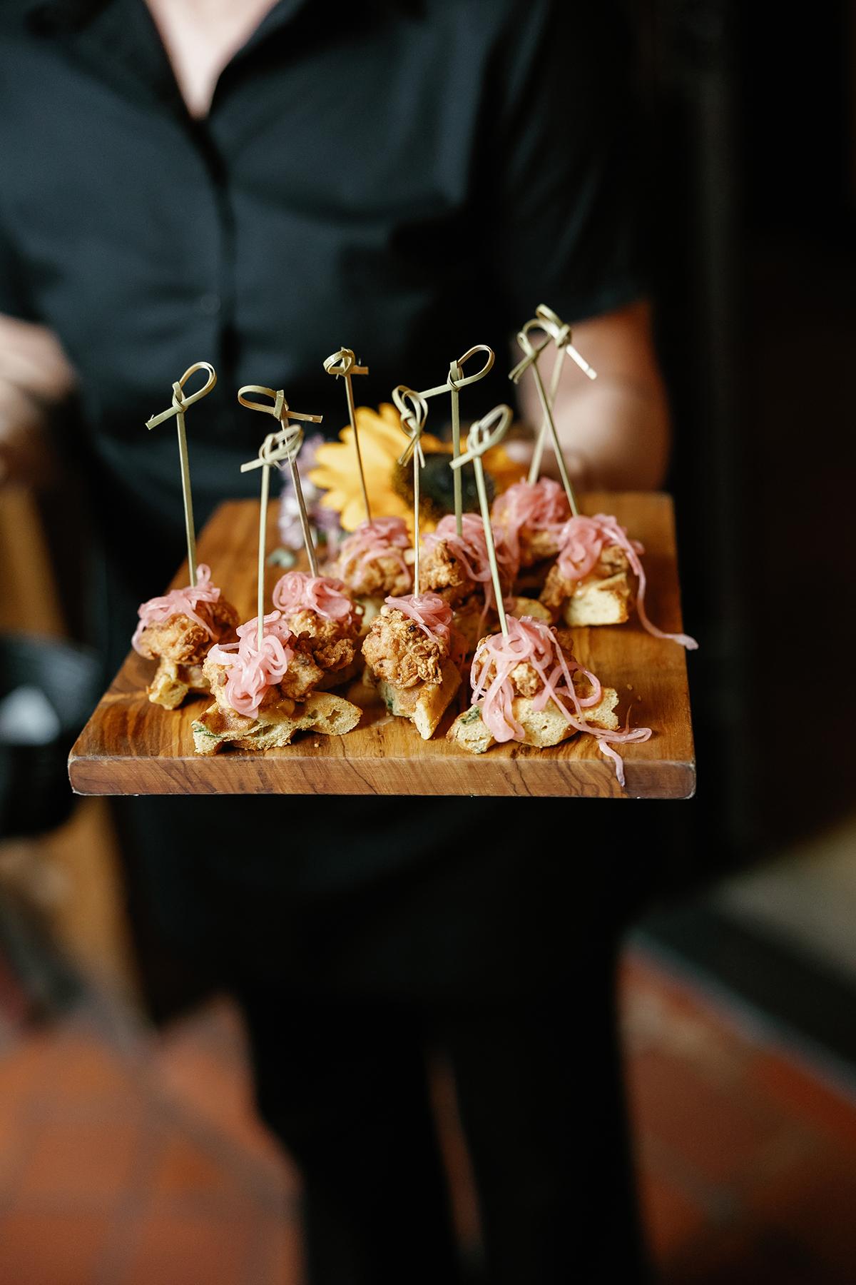Server holding appetizers on skewers