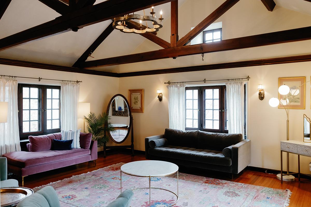 Cozy living room with vaulted ceiling, sofas, and oval mirror.