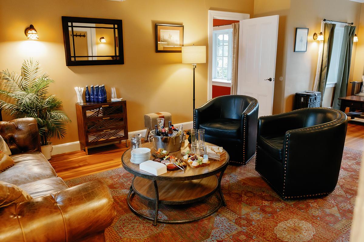 Cozy living room with leather chairs, a sofa, and a round table on a patterned rug.