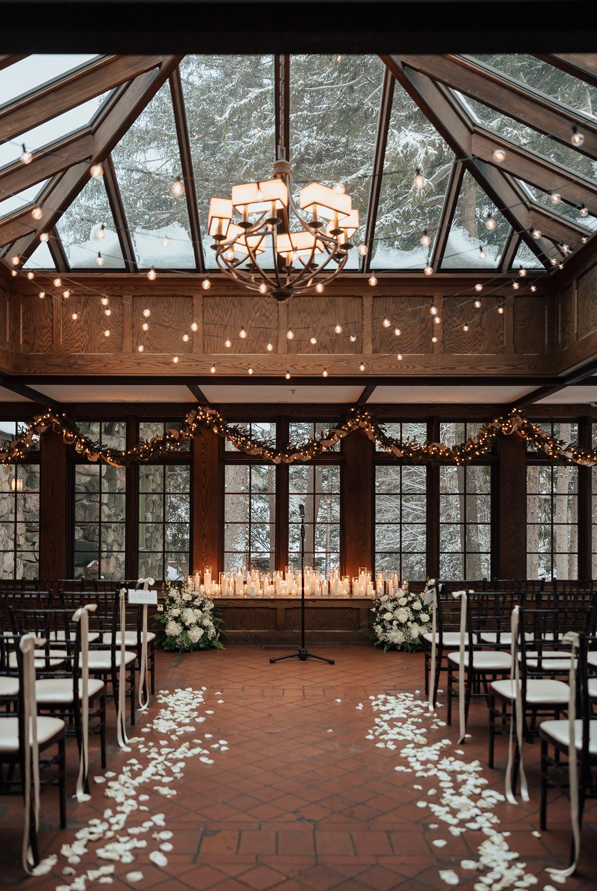 Wedding venue with candles and flower petals under a glass roof.