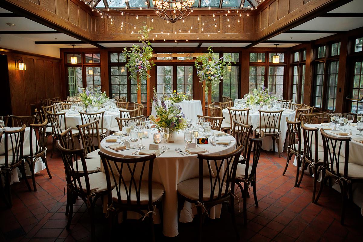 Elegant dining room with round tables, white linens, and floral centerpieces.