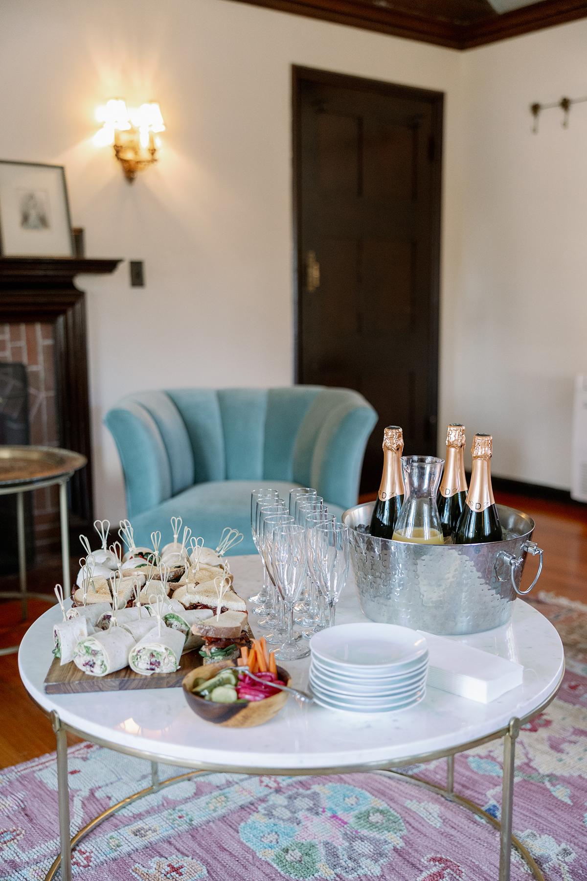 Elegant living room with a round table, snacks, and champagne on ice.
