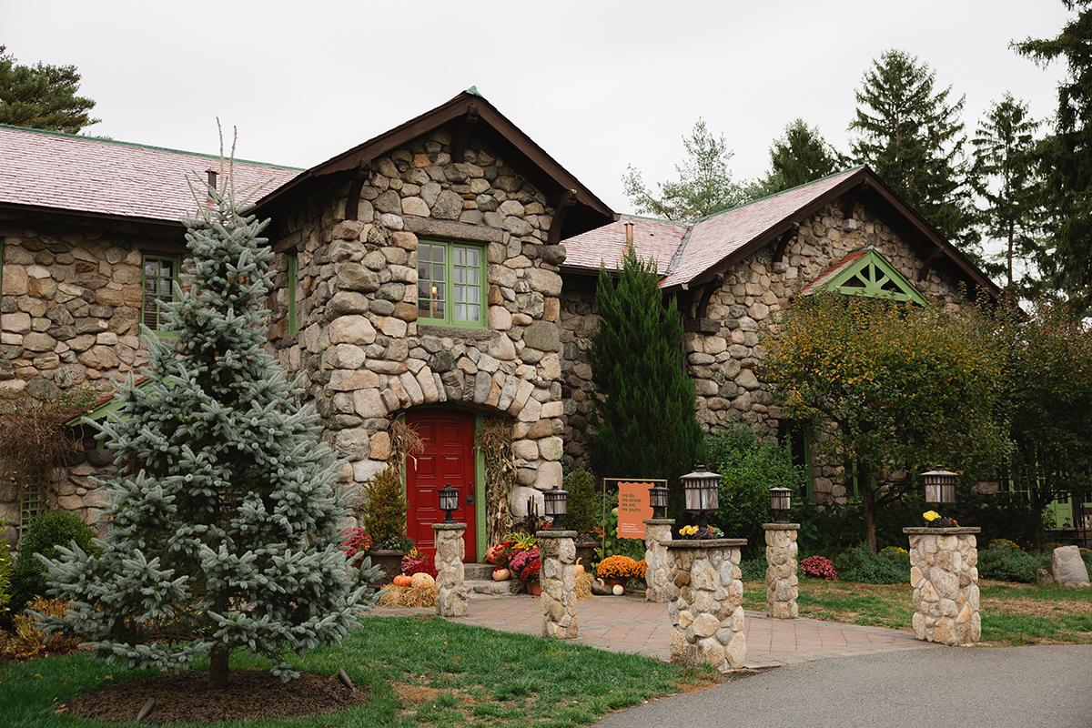 Stone building with red door, surrounded by greenery and a pathway.
