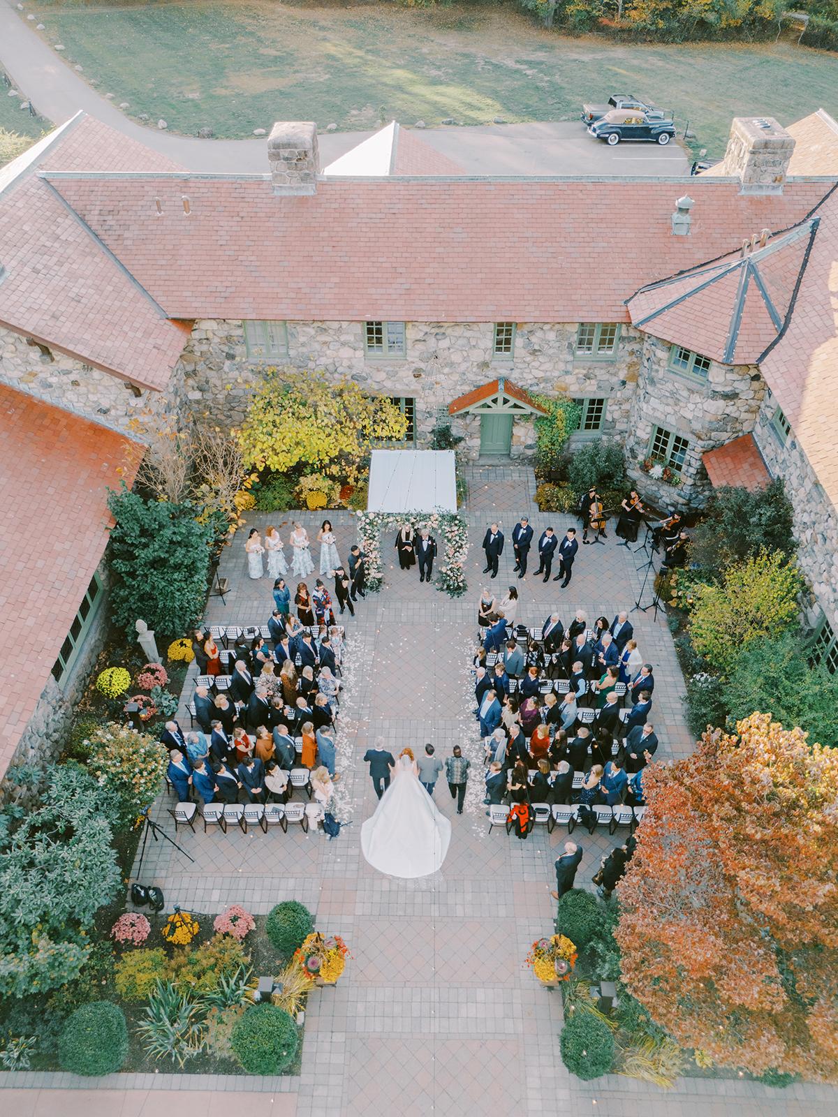Aerial view of an outdoor wedding ceremony in a courtyard.