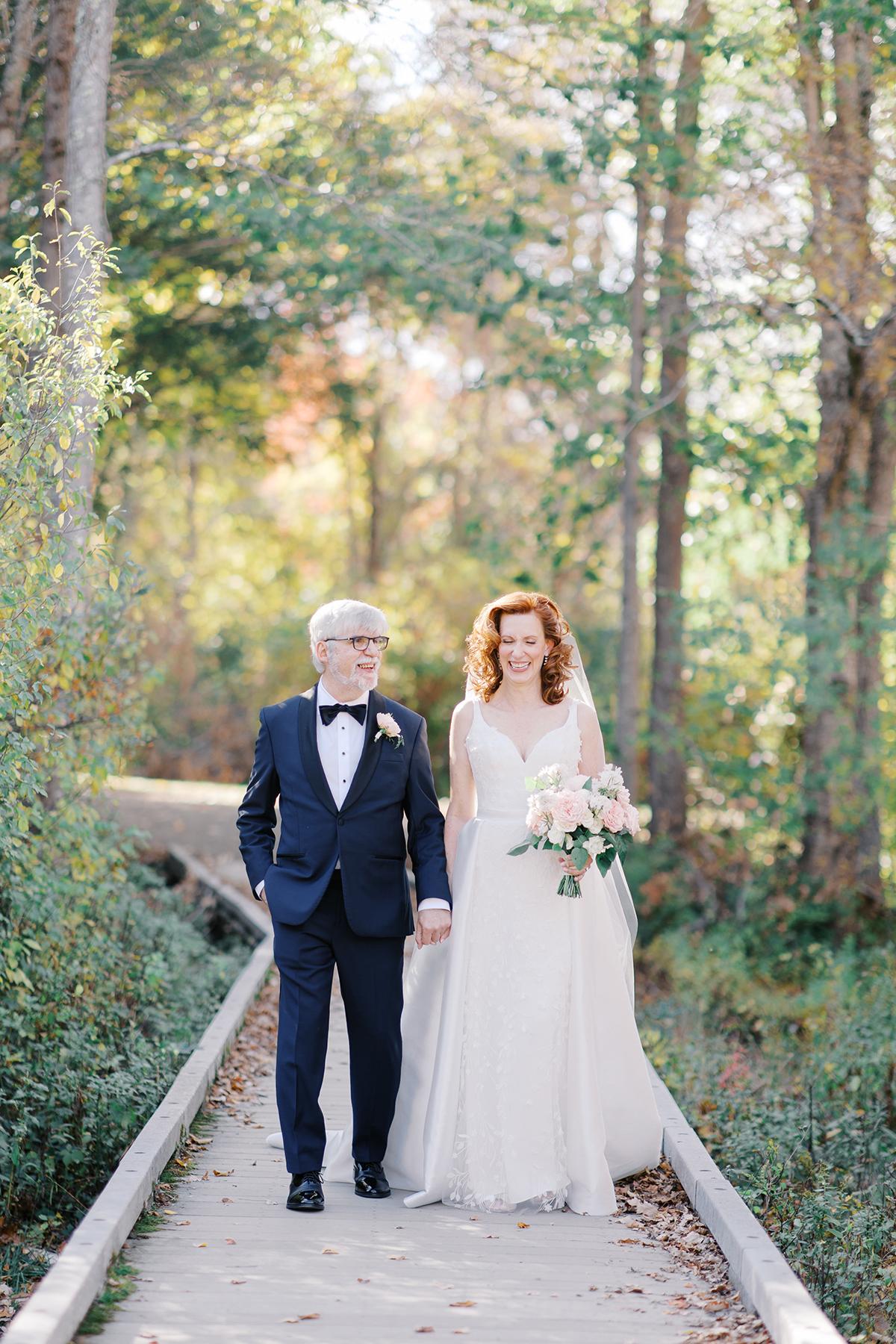 Bride and groom walking on a forest path, she holds a bouquet.