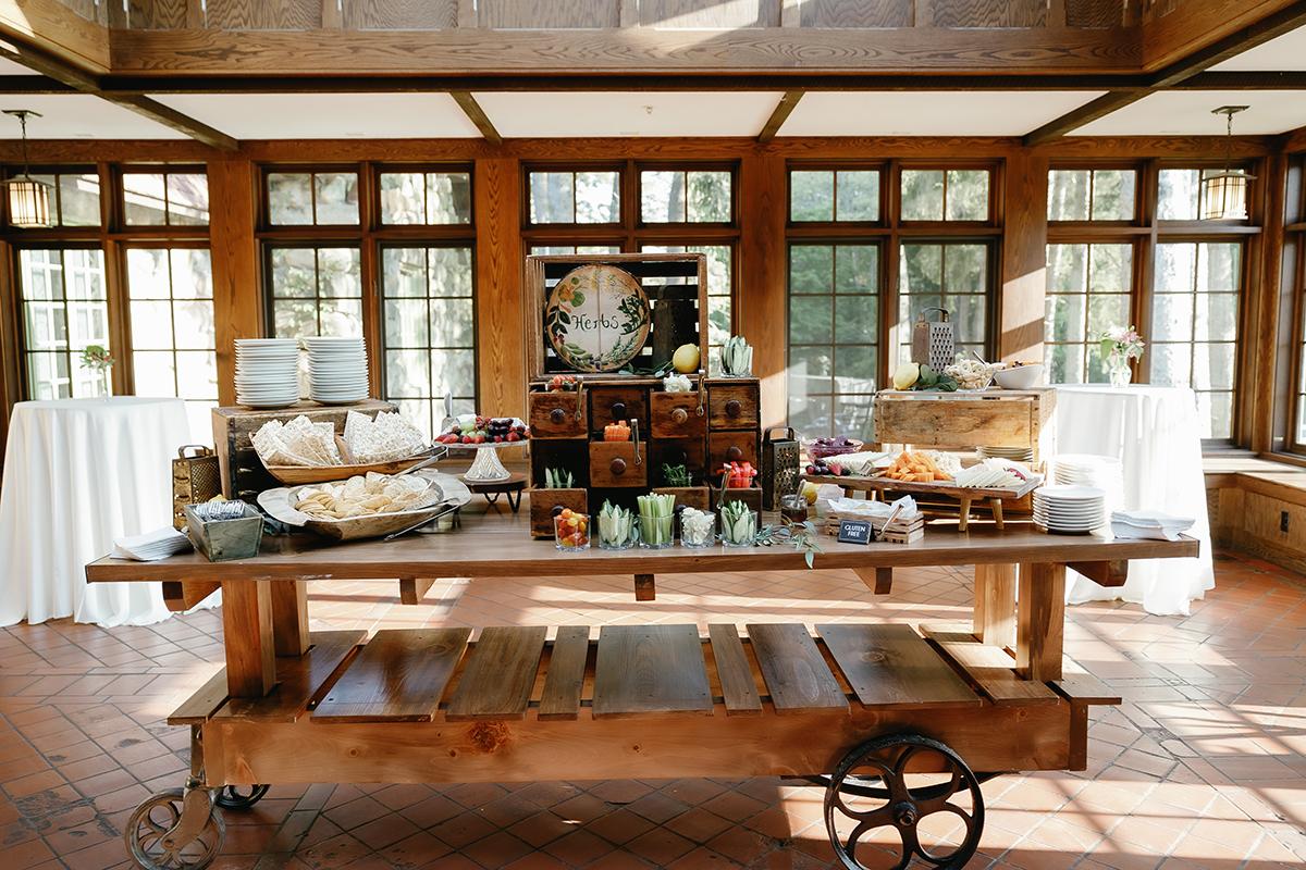 Rustic buffet table with snacks and wooden crates in a sunlit room.