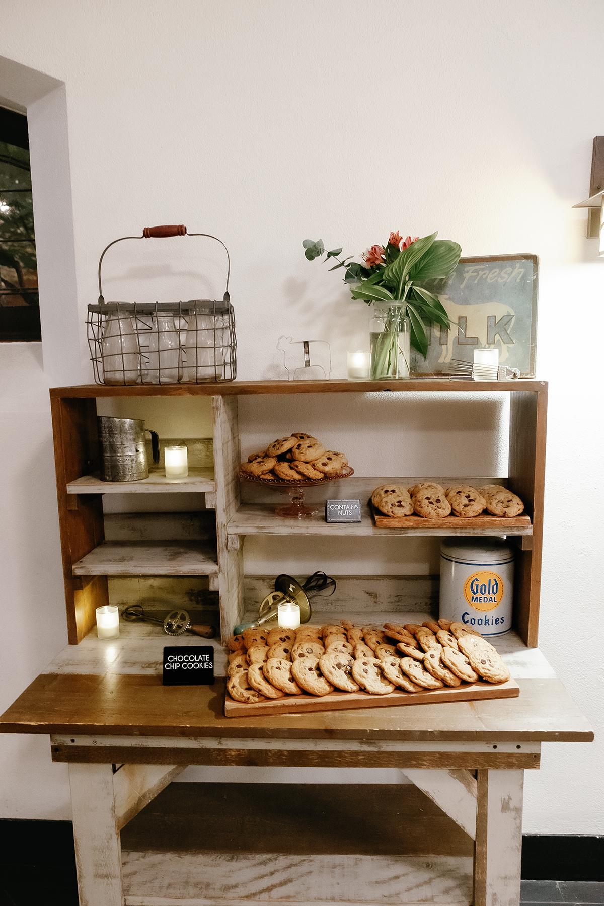 Bakery shelf with cookies, flowers, and candles.