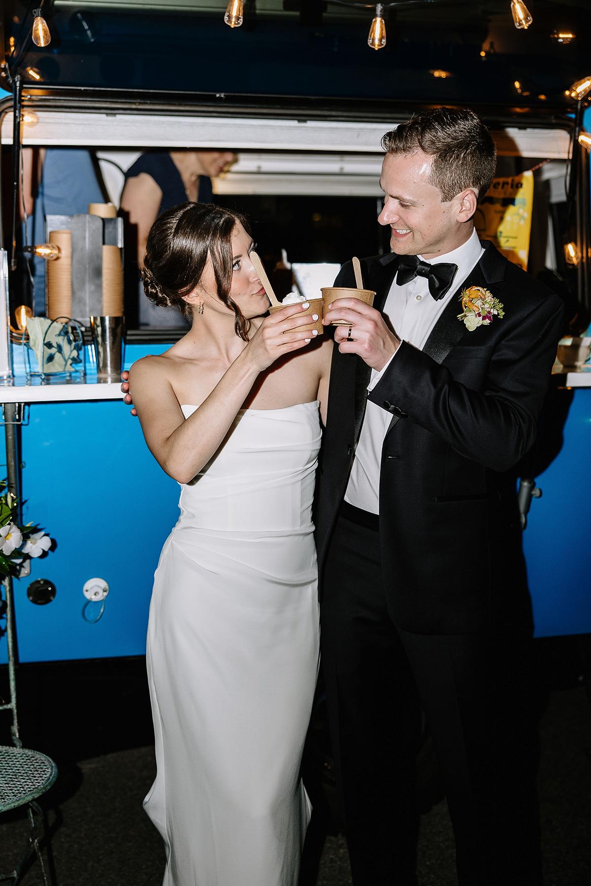 Bride and groom toasting in front of a blue food truck.