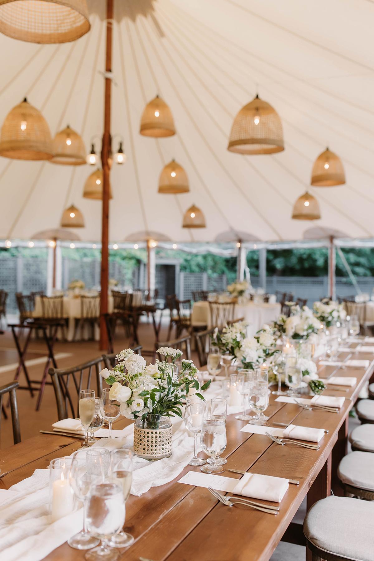 Elegant wedding table setup under a tent with hanging lights.