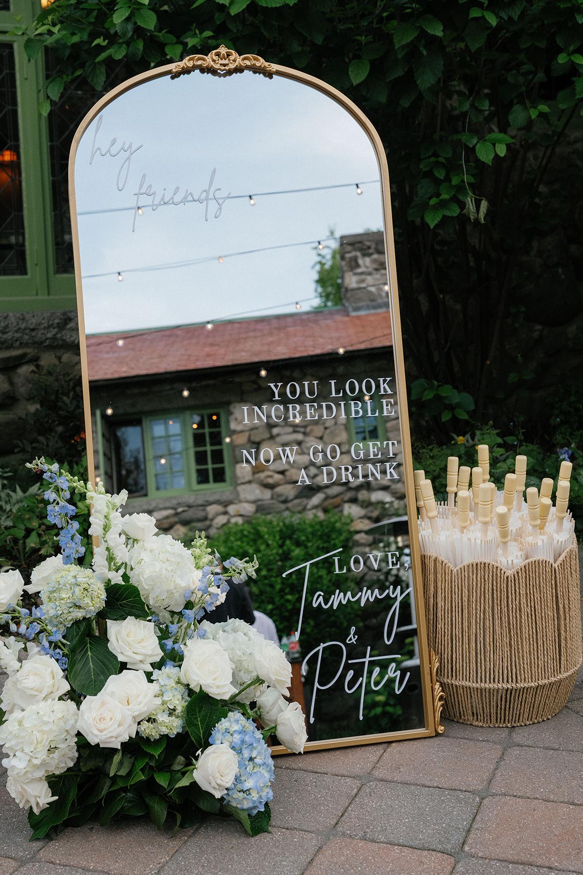 Arched mirror with white flowers and a basket of parasols nearby.