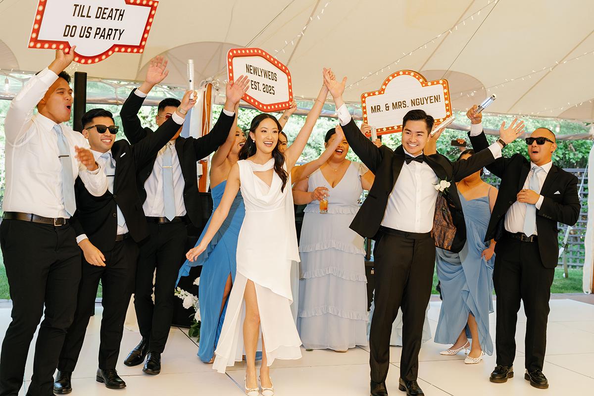 Wedding party celebrating with raised hands and signs.