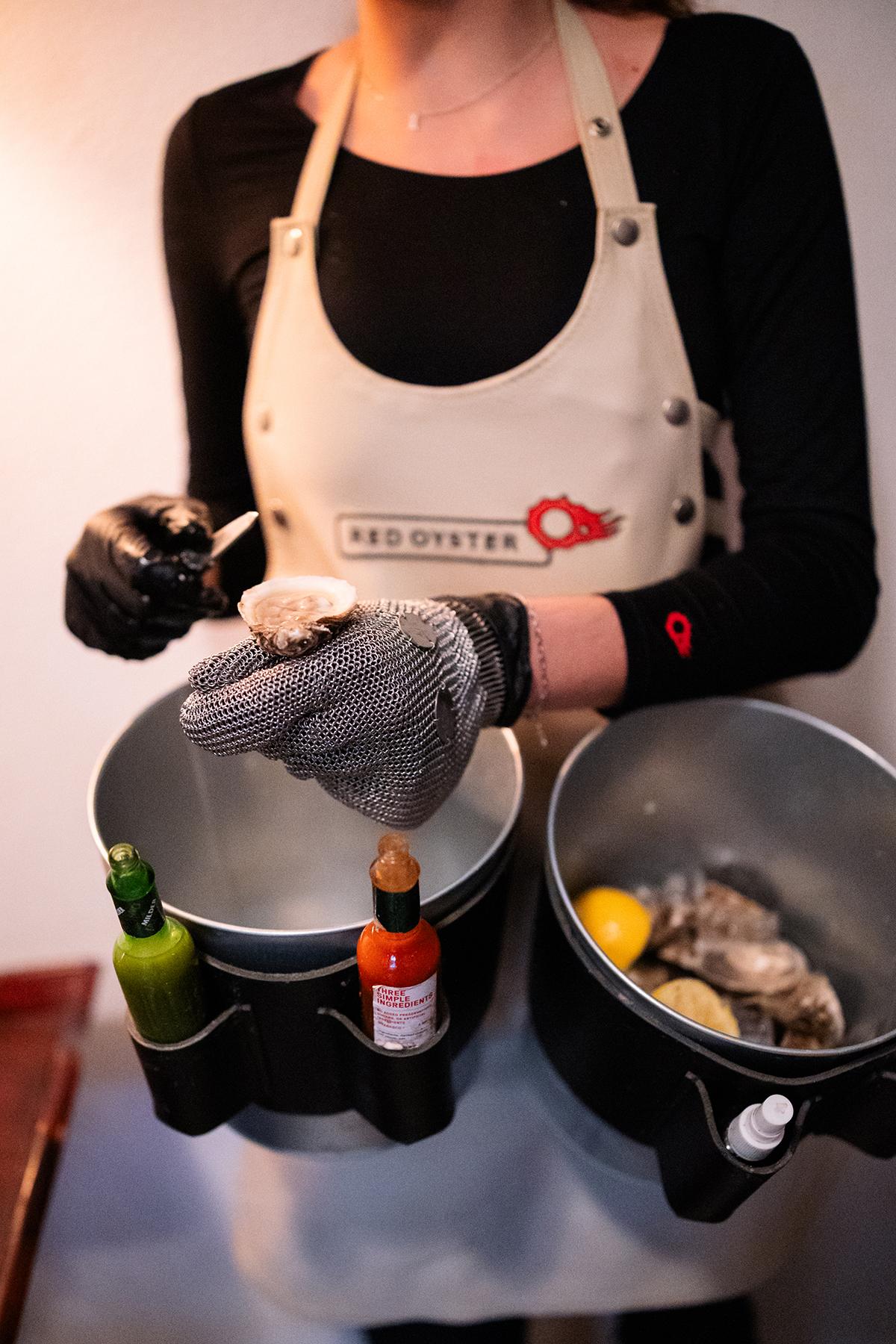 Server holding a tray with oysters, hot sauce, and lemons.