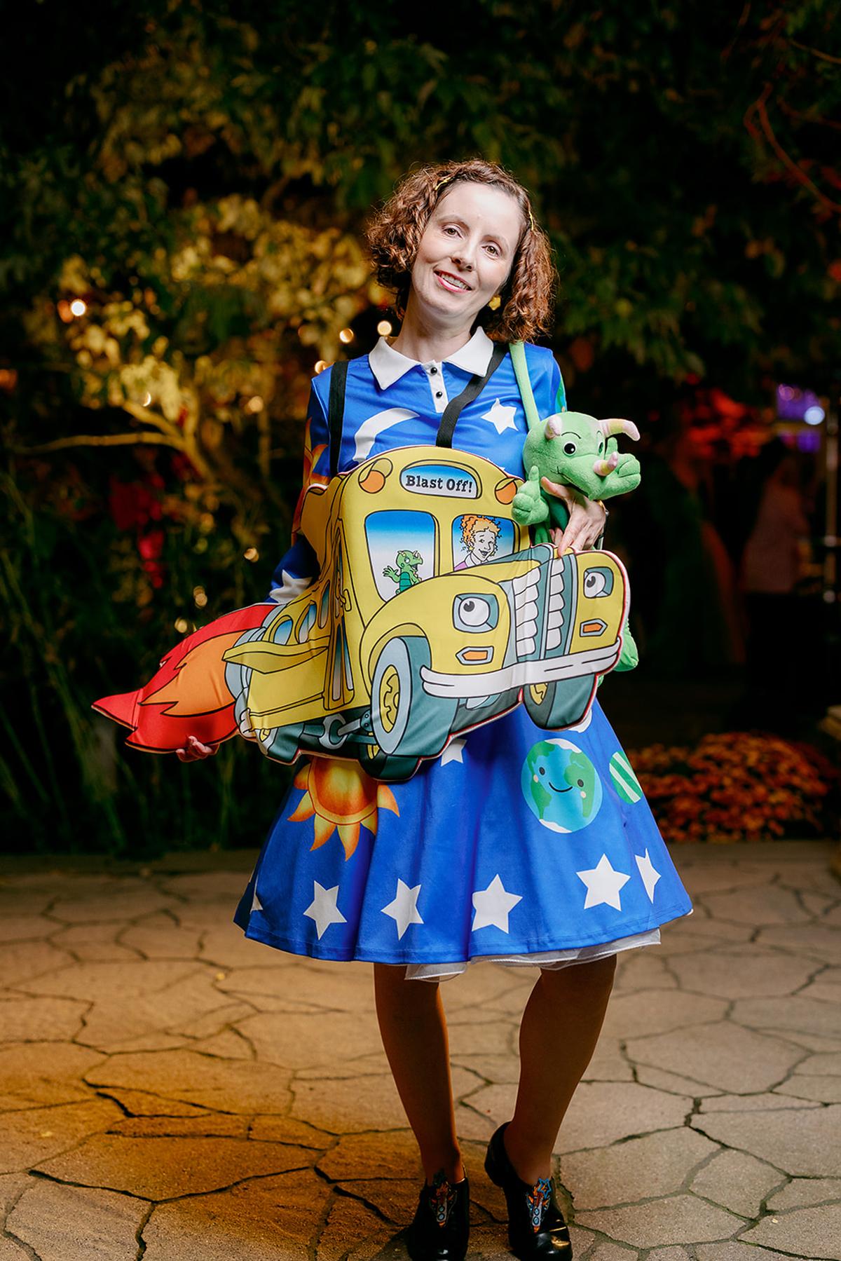 Woman in a colorful dress with stars and a bus design, smiling.