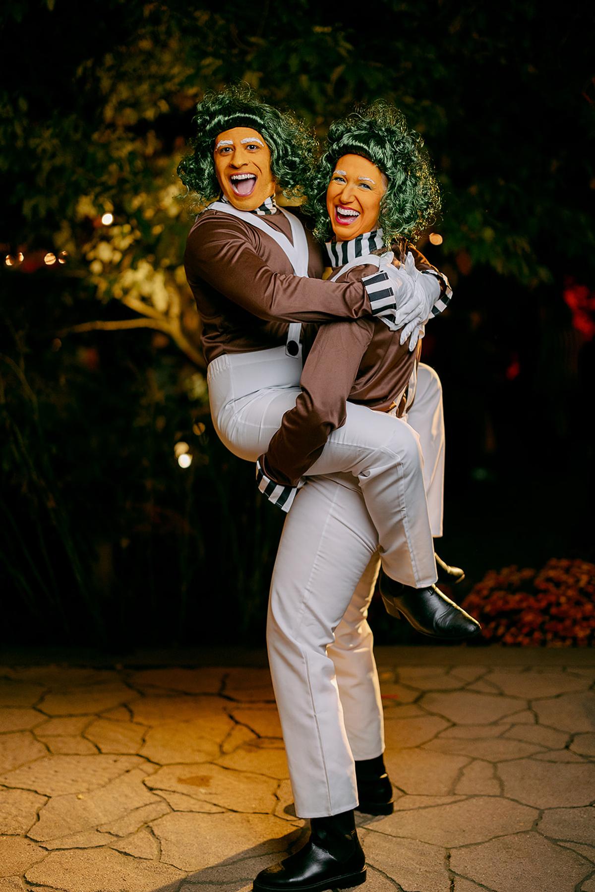 Two people in costume, smiling and hugging outdoors at night.
