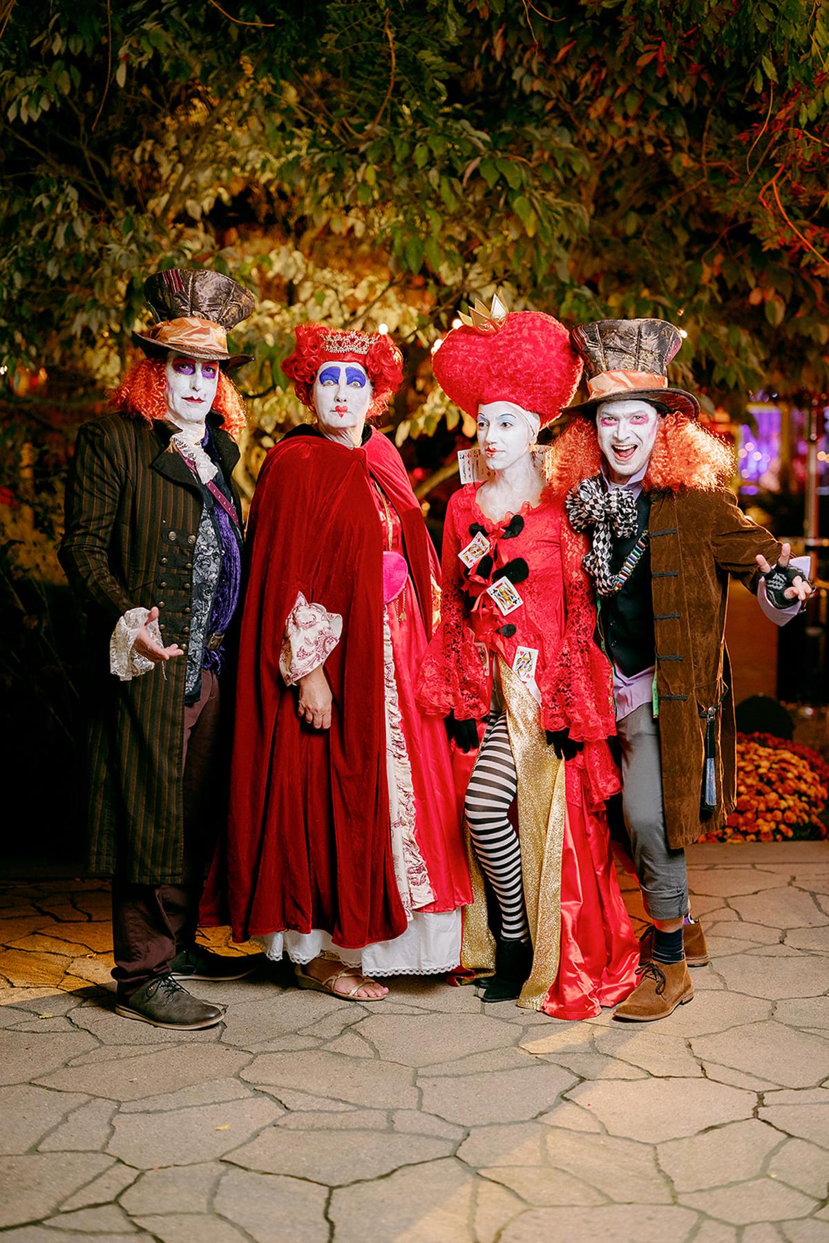 Four people in elaborate Halloween costumes with red and black details, standing outdoors.