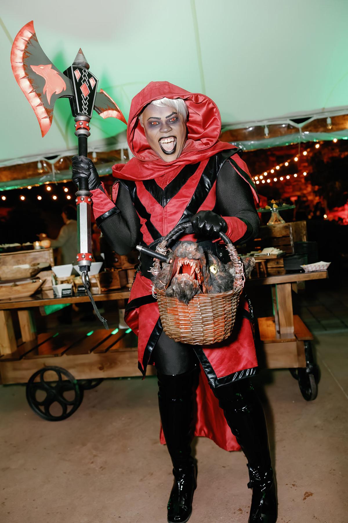Red and black devil costume with axe, holding basket, festive setting.