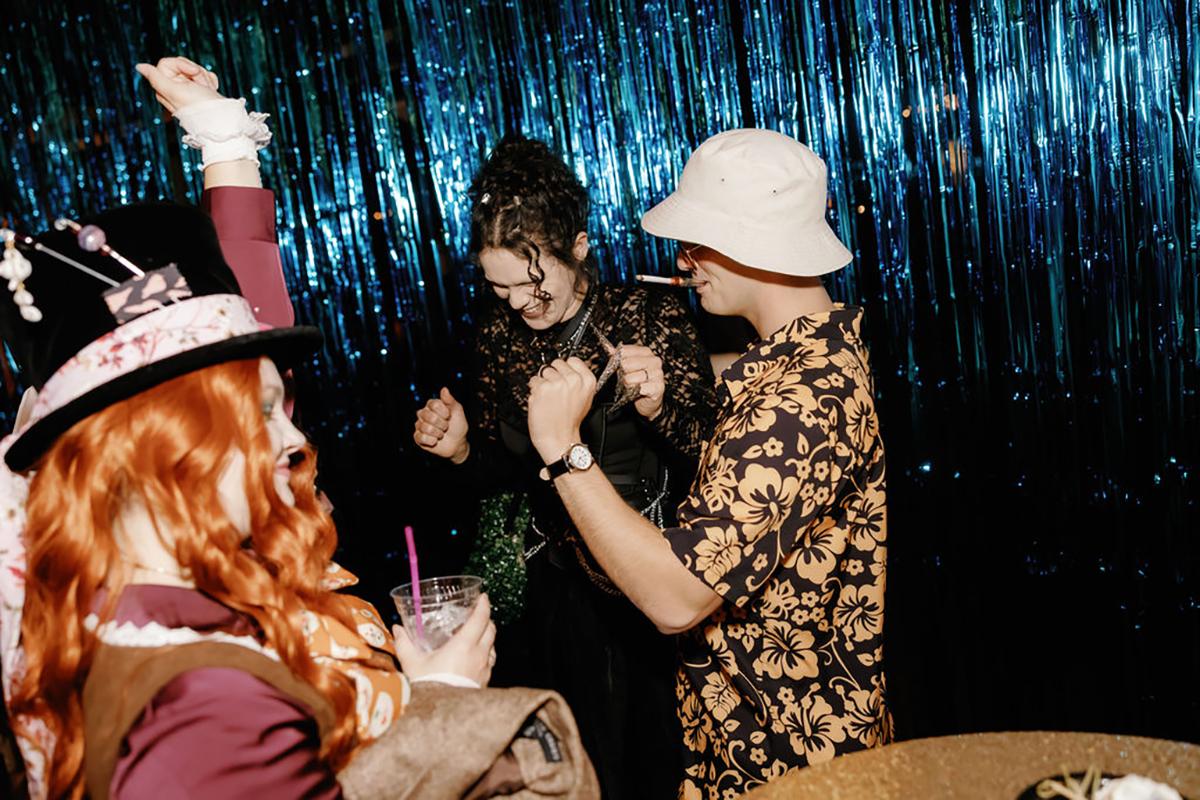 Party-goers in costumes, dancing under blue streamers.