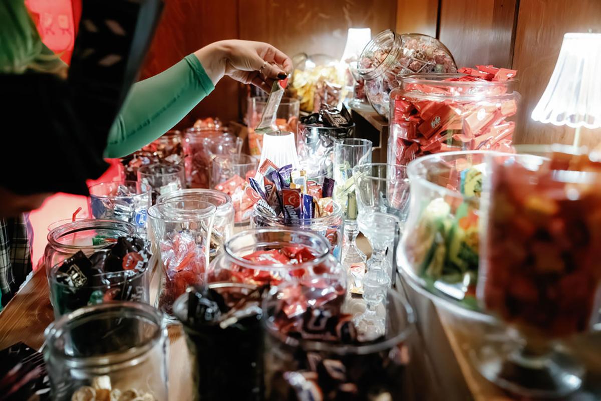 Candy buffet with jars of colorful sweets and a hand reaching for a treat.