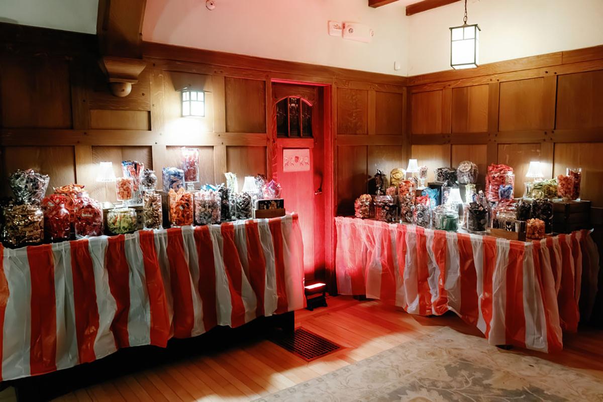 Candy buffet with red and white striped tablecloths in a dimly lit room.