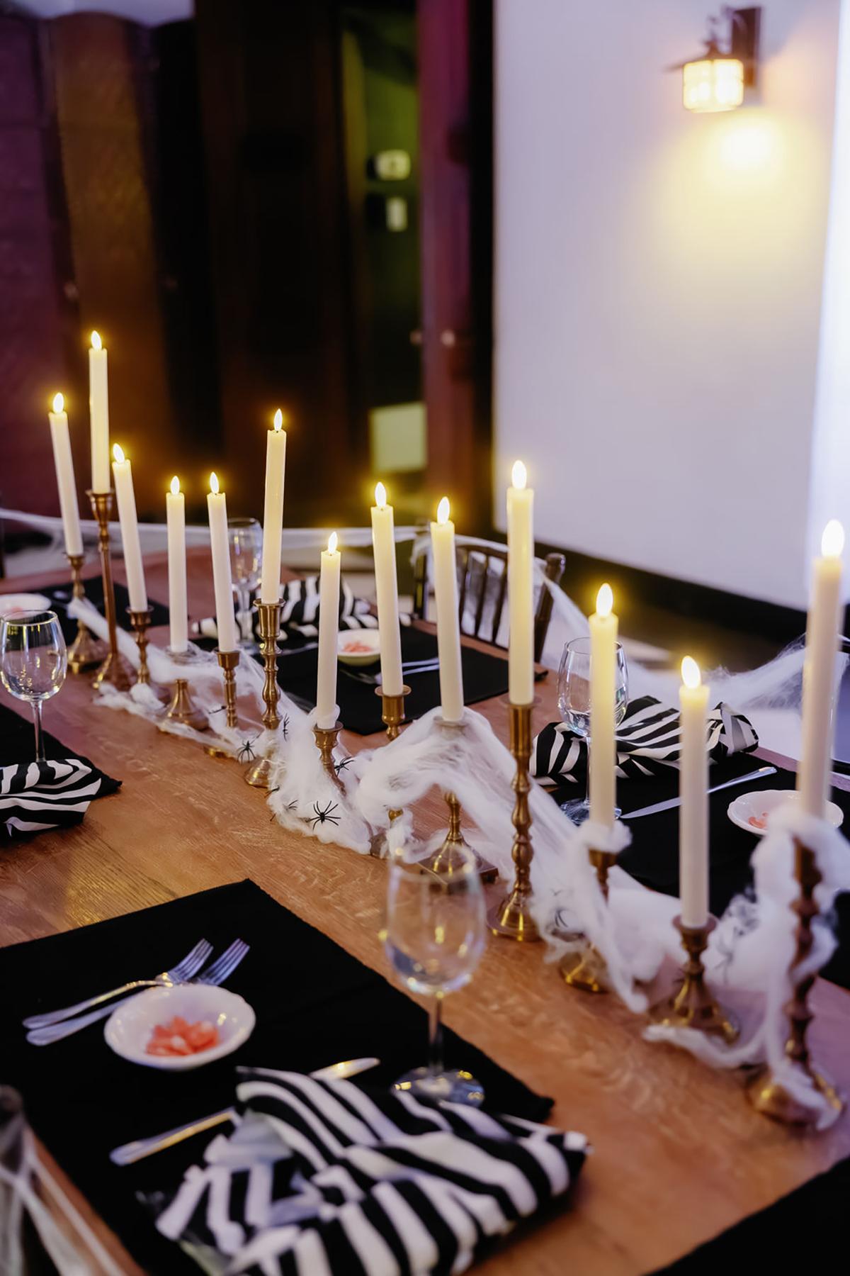 Candles lined up on a decorated dinner table with black and white linens.