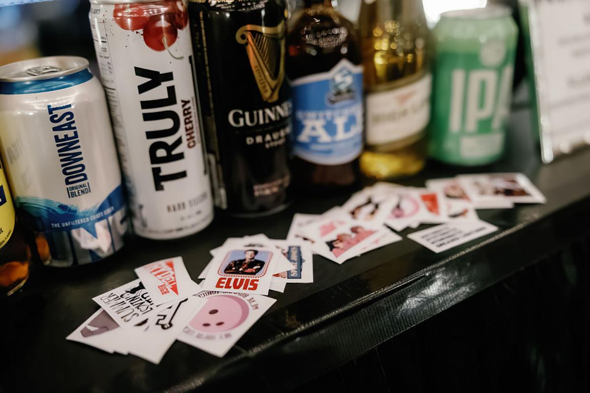 Assorted beverage cans and bottles on a counter with scattered drink coasters.
