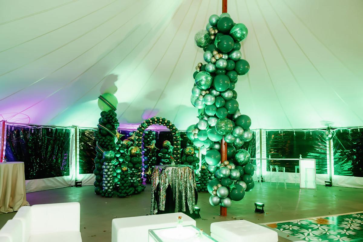 Elegant tented event space with green balloon decorations.