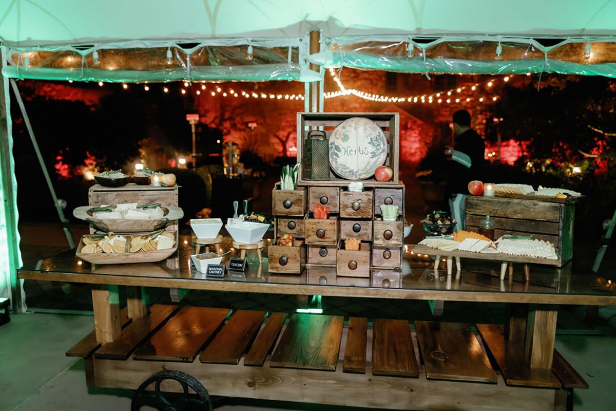 Dessert table with pastries, wooden drawers, and globe decoration at an outdoor event.