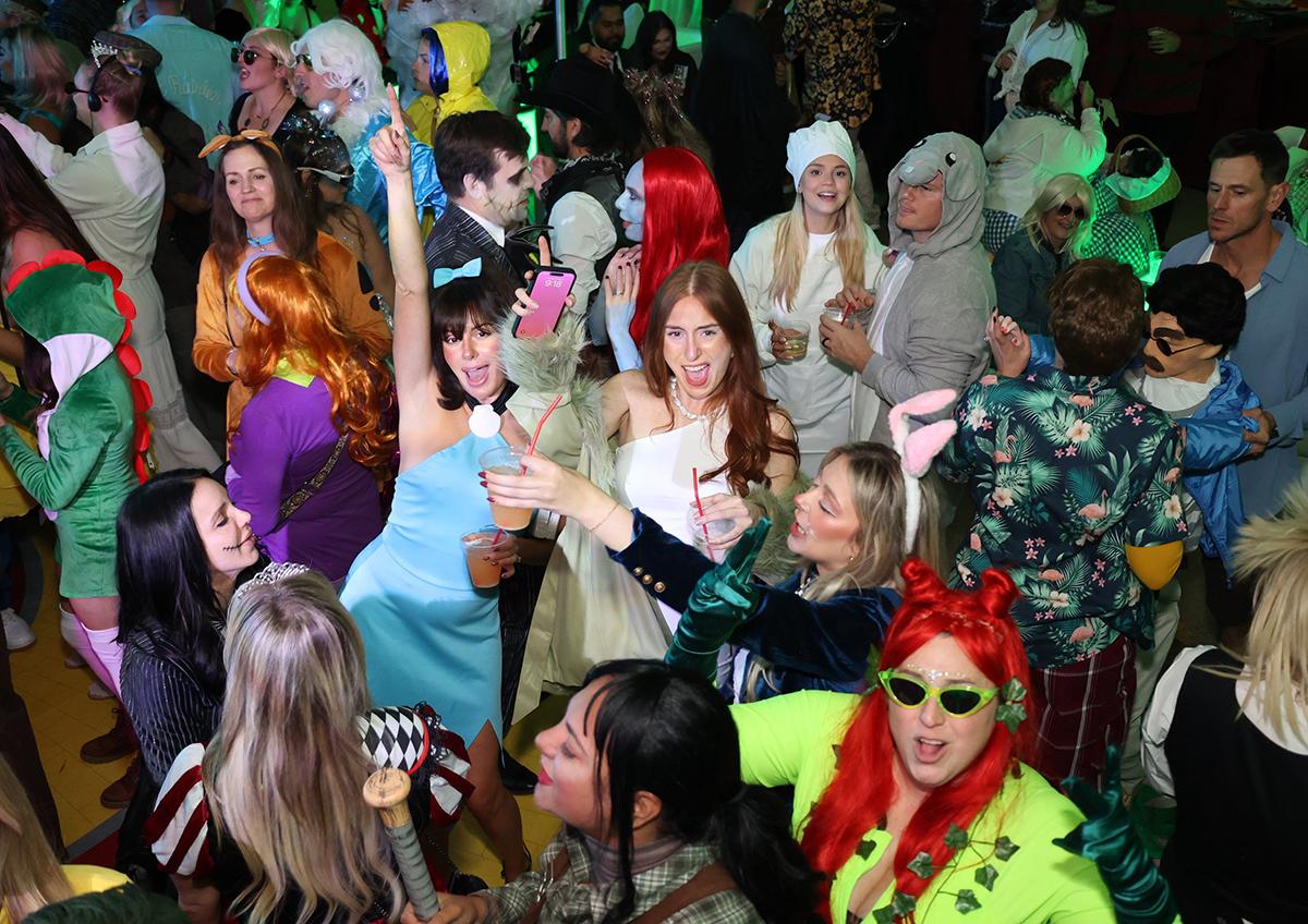 Costume party with people celebrating, wearing colorful outfits and accessories.